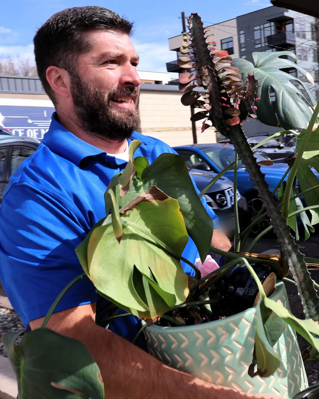 Peace of Mind mover carrying a large potted plant outdoors